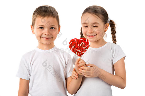 男孩给了一个小女孩糖果棒棒糖的心脏隔离在白色。 情人节`。 孩子们喜欢。