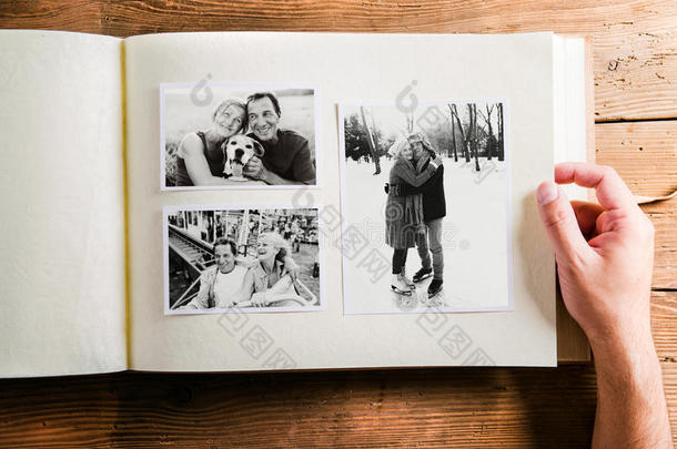 手持相册与老年夫妇的照片。 工作室