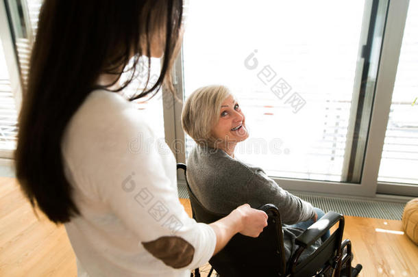 残疾的老年妇女坐在轮椅上女儿坐在轮椅上。