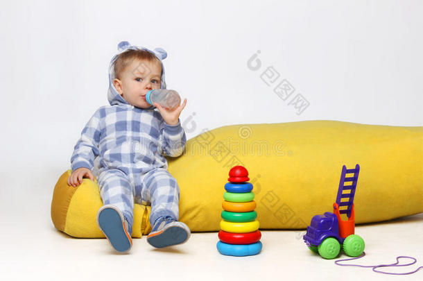 孩子，人，家庭，生活方式的概念。一个小男孩在玩玩具，喝着小口杯。