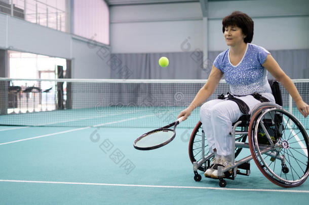 轮椅上残疾的成熟妇女在<strong>网球场</strong>上打网球