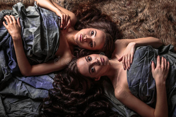 美丽的双胞胎，年轻的女人，自然的化妆和发型，躺在他们的卷发周围
