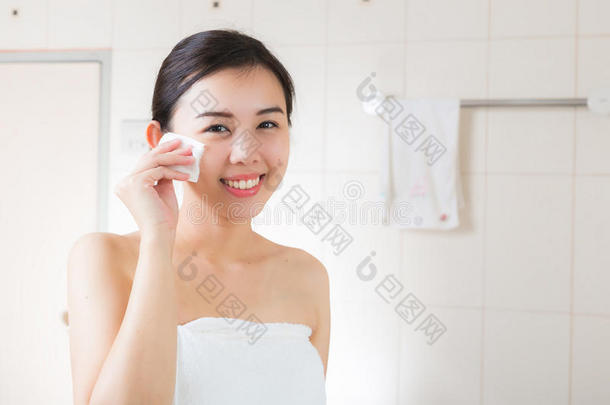 漂亮的女人在浴室里从脸上卸妆。