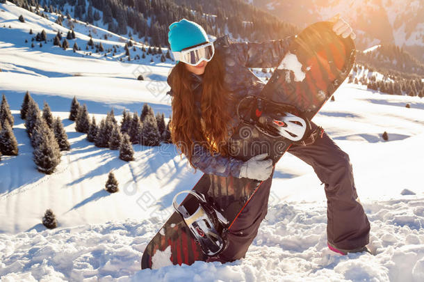 女孩滑雪者站在山顶，手里拿着滑雪板。