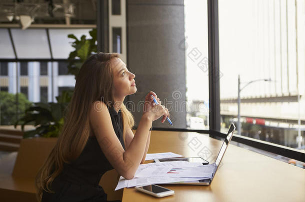 在办公室工作的女商人看着窗外