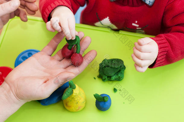 儿童`和成人的手从粘土中塑造