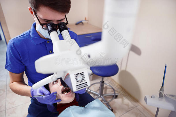 牙医看显微镜看病人`牙齿