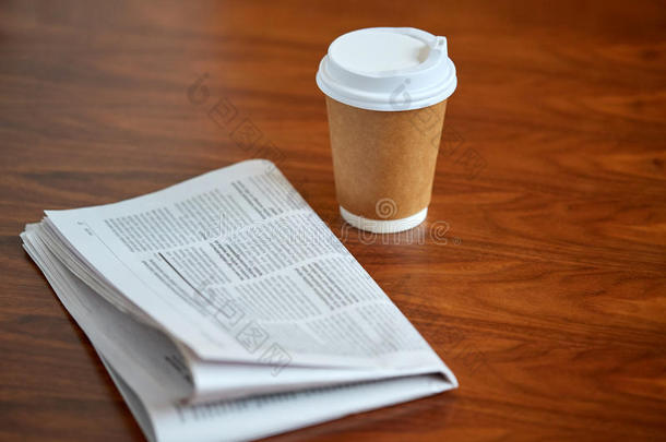 纸杯里的咖啡饮料和桌子上的报纸