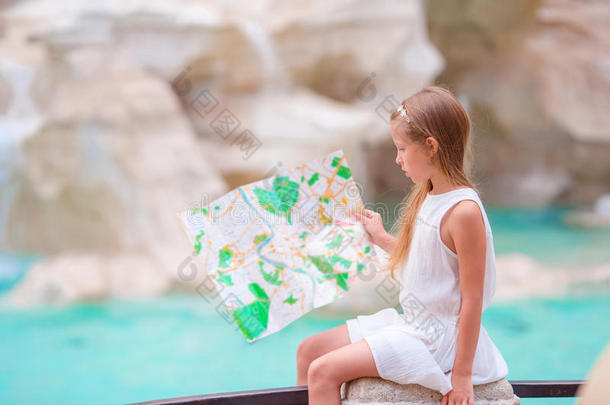 可爱的女孩看着罗马特雷维喷泉附近的旅游地图。 快乐的托德勒孩子在欧洲享受意大利的假期。