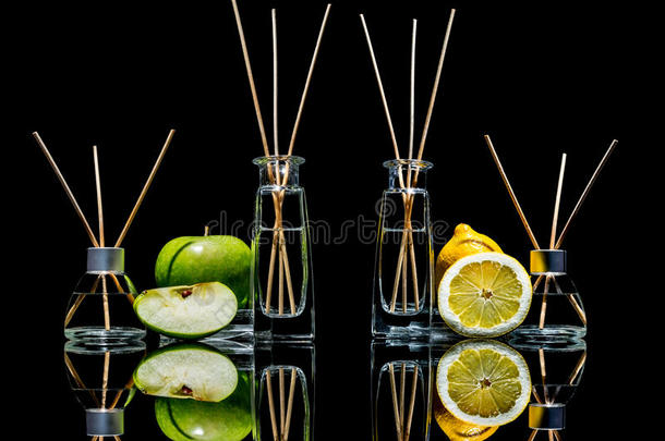 空气<strong>清新</strong>剂在玻璃瓶与棍子和柠檬，<strong>绿色</strong>苹果与反射隔离在黑色
