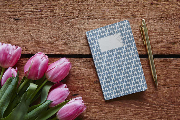 一束粉红色的郁金香在笔记本上写着春天的气氛