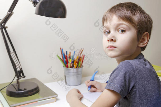男孩坐在家里的书桌前做作业。 孩子在写。 <strong>学校</strong>，孩子，教育<strong>理念</strong>