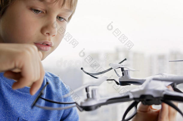 孩子玩无人机。 靠近窗户的男孩手里拿着四架直升机。 技术，休闲玩具概念
