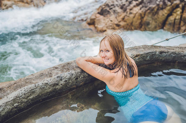地热温泉。 女人在温泉池里放松，背景是瀑布