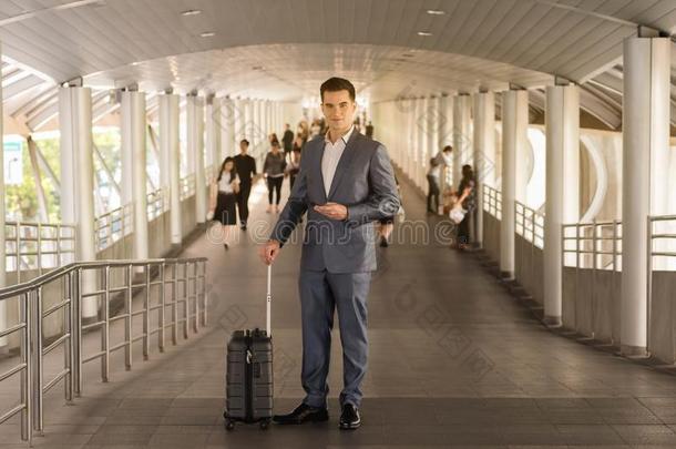 带旅行袋的商人在步行途中使用智能手机