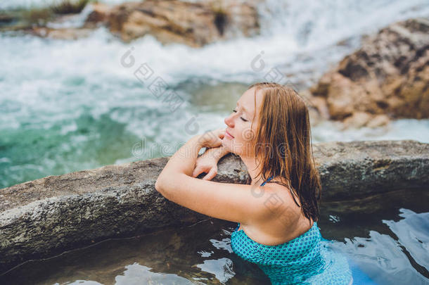 地热温泉。 女人在温泉池里放松，背景是瀑布