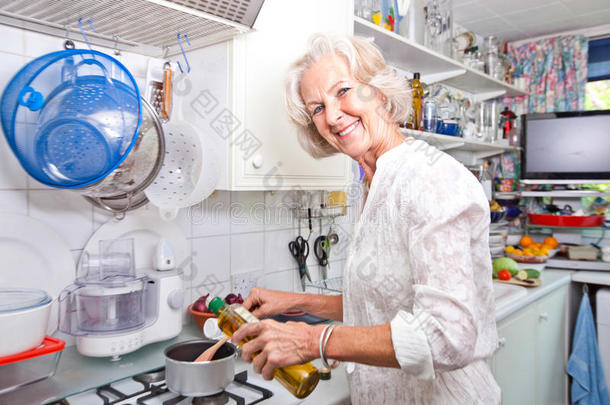 家政厨房老太太往锅里倒橄榄油的画像