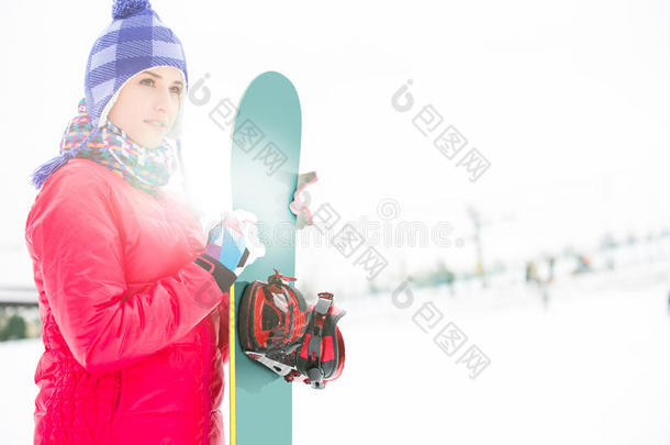 美丽的年轻女子穿着温暖的衣服在冬天举着滑雪板