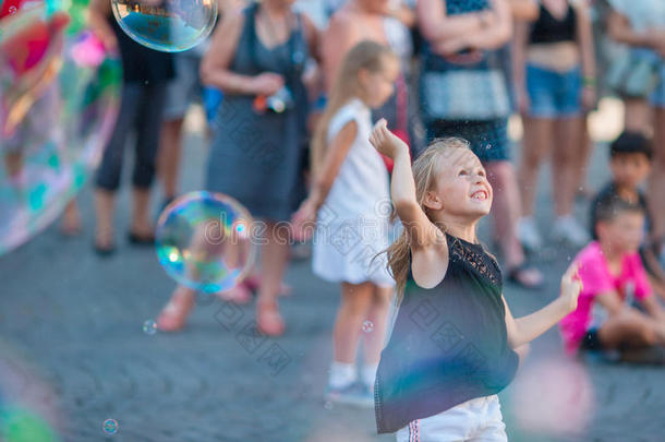 可爱的小女孩在欧洲城市吹肥皂泡。 快乐的孩子在意大利享受暑假