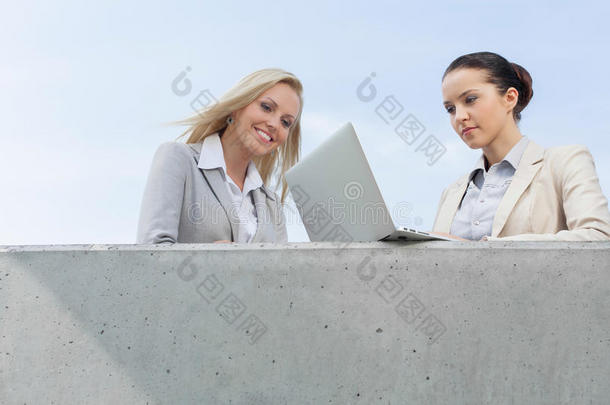 女商人与同事站在天台上用笔记本电脑俯视