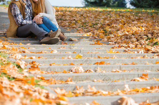 秋天，一对夫妇坐在公园台阶上的低处