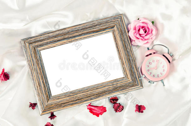空白木制相框和粉红色闹钟与玫瑰。
