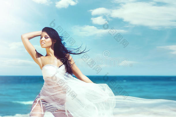 美丽的女孩在海滩上穿着白色泳衣。 旅行，假期，假期，概念。