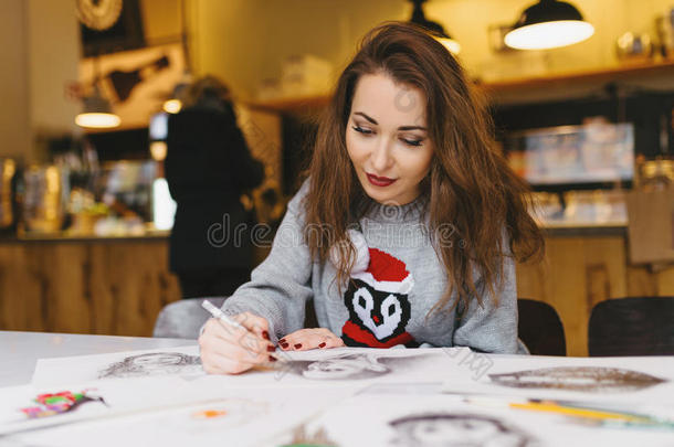 漂亮的女孩在咖啡馆里用<strong>铅笔画画</strong>