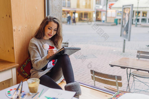 漂亮的女孩在咖啡馆里用铅笔画画