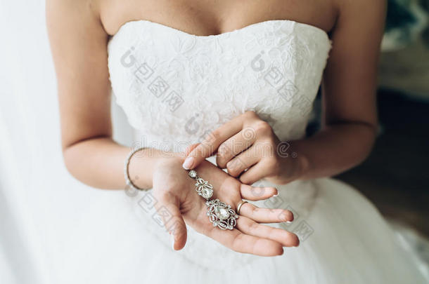 优雅的新娘戴着银耳环。 温柔的手和珠宝。