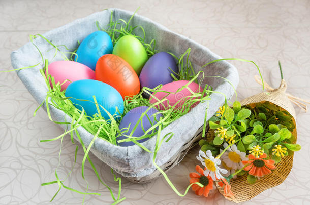 复活节柳条篮子，彩色鸡蛋和一束春天的花在白板上。