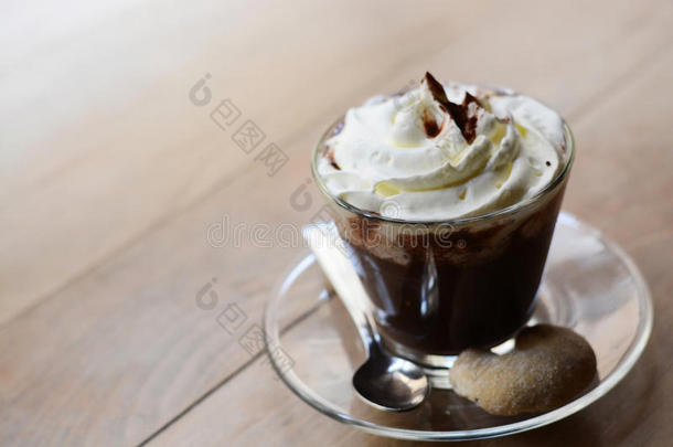 在木桌上特写一杯加生奶油和可可粉的热巧克力