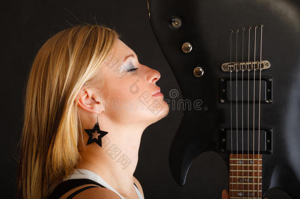 金发女子手持电吉他，黑色背景