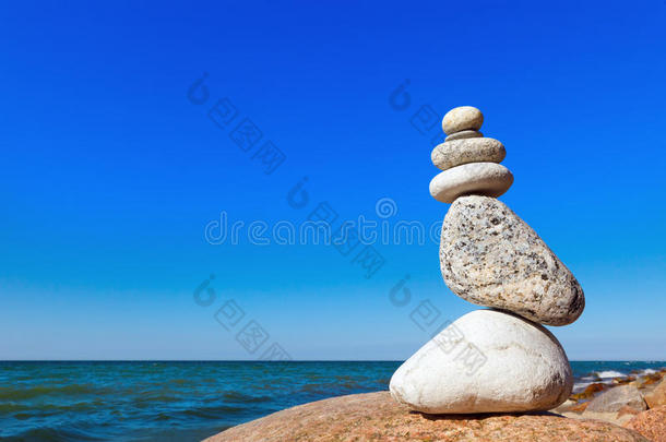 蓝天和大海背景上白色石头的平衡