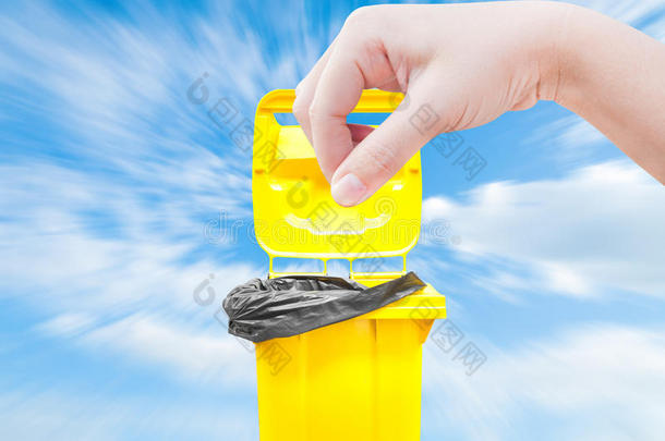 手中的女人在蓝天上挑选渔获物，黄色的垃圾箱