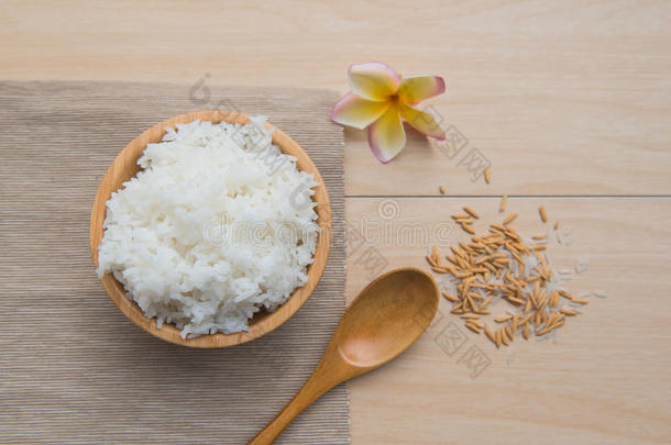 在木碗和勺子里煮米饭，在木头背景上煮米饭。