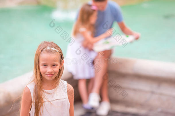 家庭与旅游地图附近的丰塔纳迪特雷维，罗马，意大利。 特雷维喷泉小女孩背景的肖像。