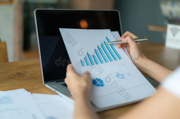 商务女士把财务图表和笔记本电脑放在桌子上。