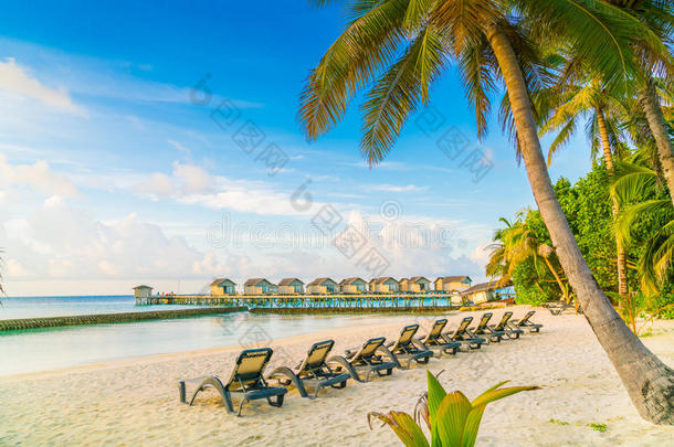 马尔代夫岛的海滩椅子和日出时的水上别墅