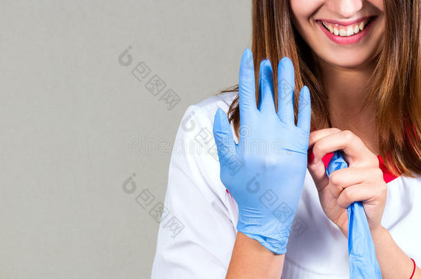 一位女医生的手和脸特写，戴上无菌手套