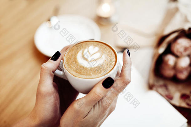 一杯<strong>咖啡</strong>卡布奇诺在女人手中，从上面看，玫瑰<strong>花</strong>在<strong>咖啡</strong>馆