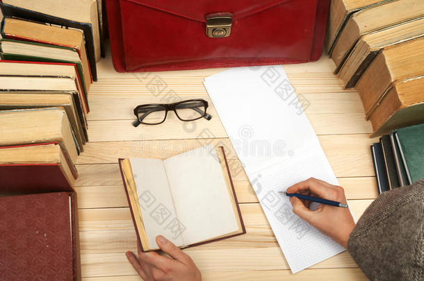 遵<strong>守法</strong>律。 坐在桌子旁的专业律师签署文件。 在木桌上的书，文件，眼镜，红布里
