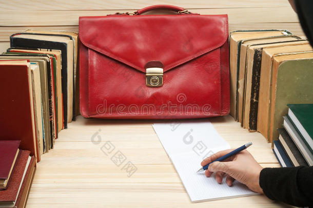 遵守法律。 坐在桌子旁的专业律师签署文件。 在木桌上的书，文件，红色公文包。 Co