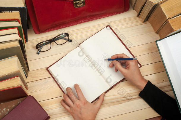 遵守法律。 坐在桌子旁的专业律师签署文件。 在木桌上的书，文件，眼镜，红布里