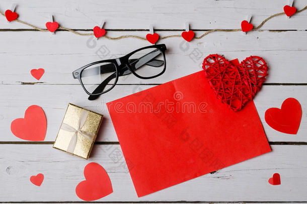白色木制背景上的红色纸片和礼品盒。