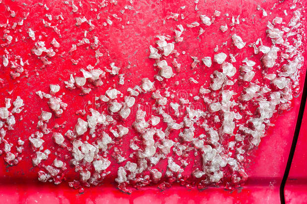 冬天在一辆红色的汽车上下雨后的新鲜白冰。 在寒冷的冬天早晨，一辆冰冻的汽车的侧面