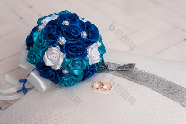 蓝色婚礼花束和结婚戒指在枕头上