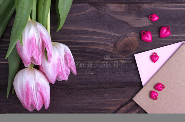 美丽的粉红色郁金香与木制背景与信封和紫色的心。 复制空间。 情人节。婚礼