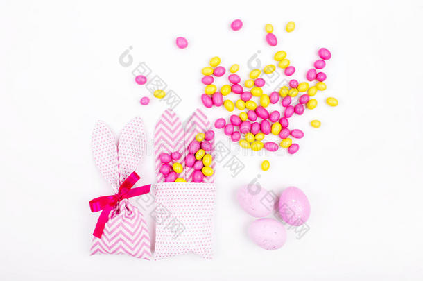 兔子在白色背景上用粉红色的糖果和鸡蛋处理袋子；