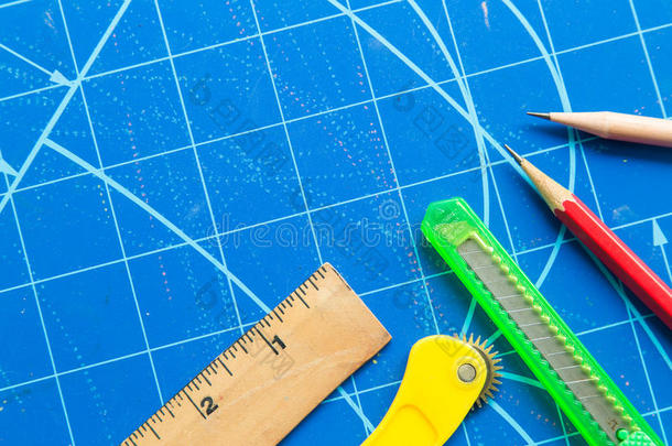 尺子，剪刀，切割机，铅笔在蓝色切割垫上的特写